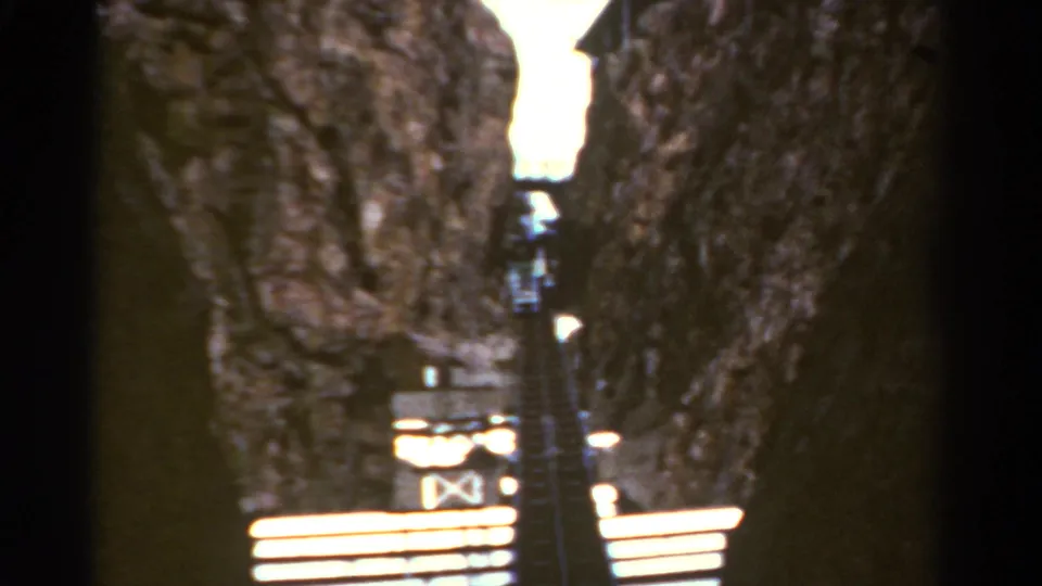 1967 Colorado 8mm frame with a steep stairway running upward between close rock walls toward bright daylight.