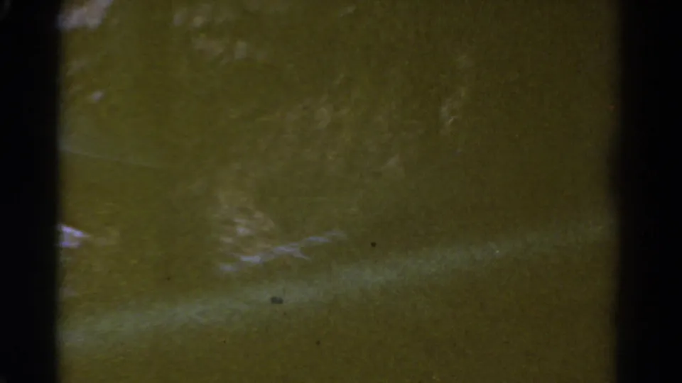 Soft 1967 8mm frame with a greenish cast, indistinct outdoor texture, and visible dust or film specks.