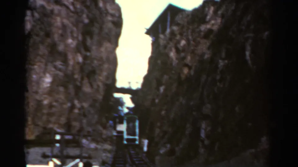 1967 Colorado 8mm frame showing a cable car or funicular ascending between dark rock walls beneath a bright sky.