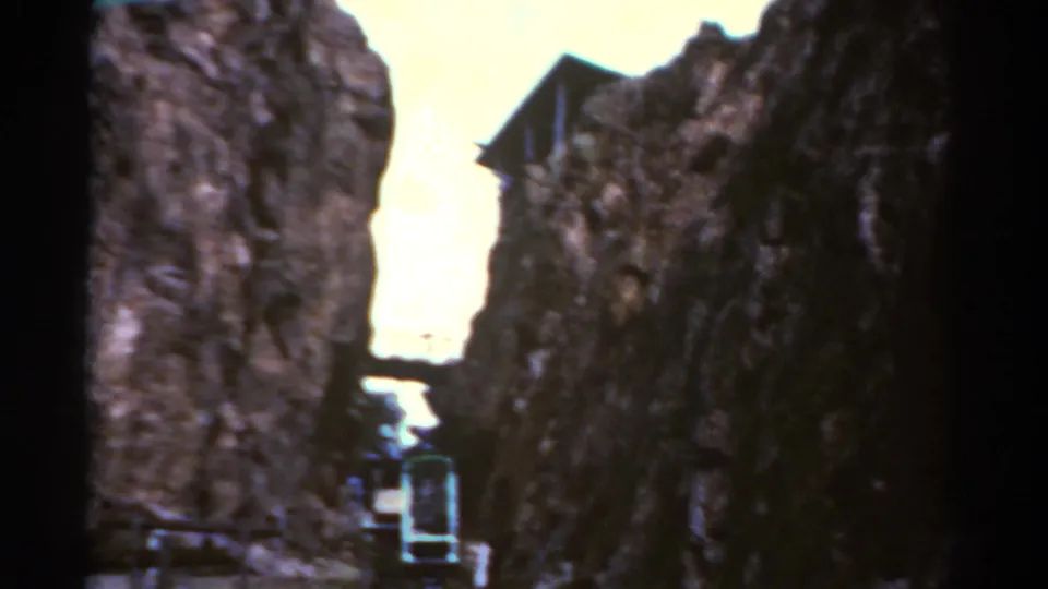 1967 Colorado 8mm frame looking up through a rocky chasm toward a small ascending cable car or funicular.