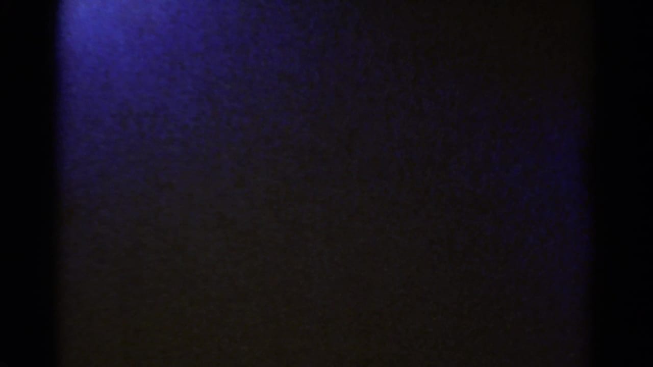 Opening 1967 8mm frame from the Colorado clip, mostly obscured by dark film edge with a blue-purple exposed area at left.