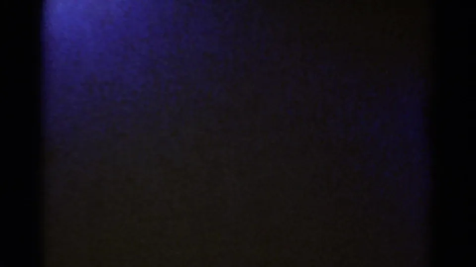 Opening 1967 8mm frame from the Colorado clip, mostly obscured by dark film edge with a blue-purple exposed area at left.