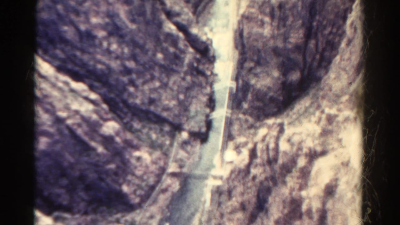 1967 Colorado 8mm view of steep rocky terrain with a narrow pale water channel running through the canyon below.
