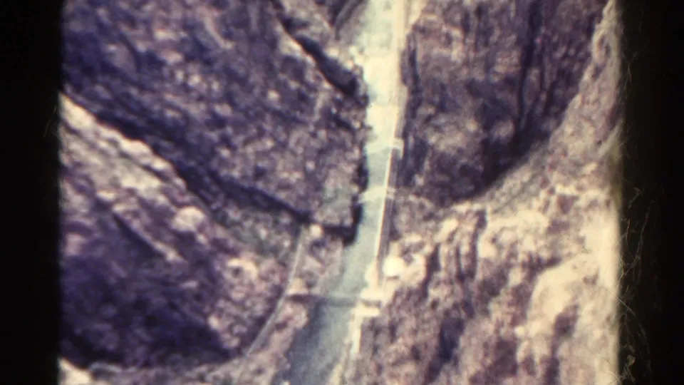 1967 Colorado 8mm view of steep rocky terrain with a narrow pale water channel running through the canyon below.