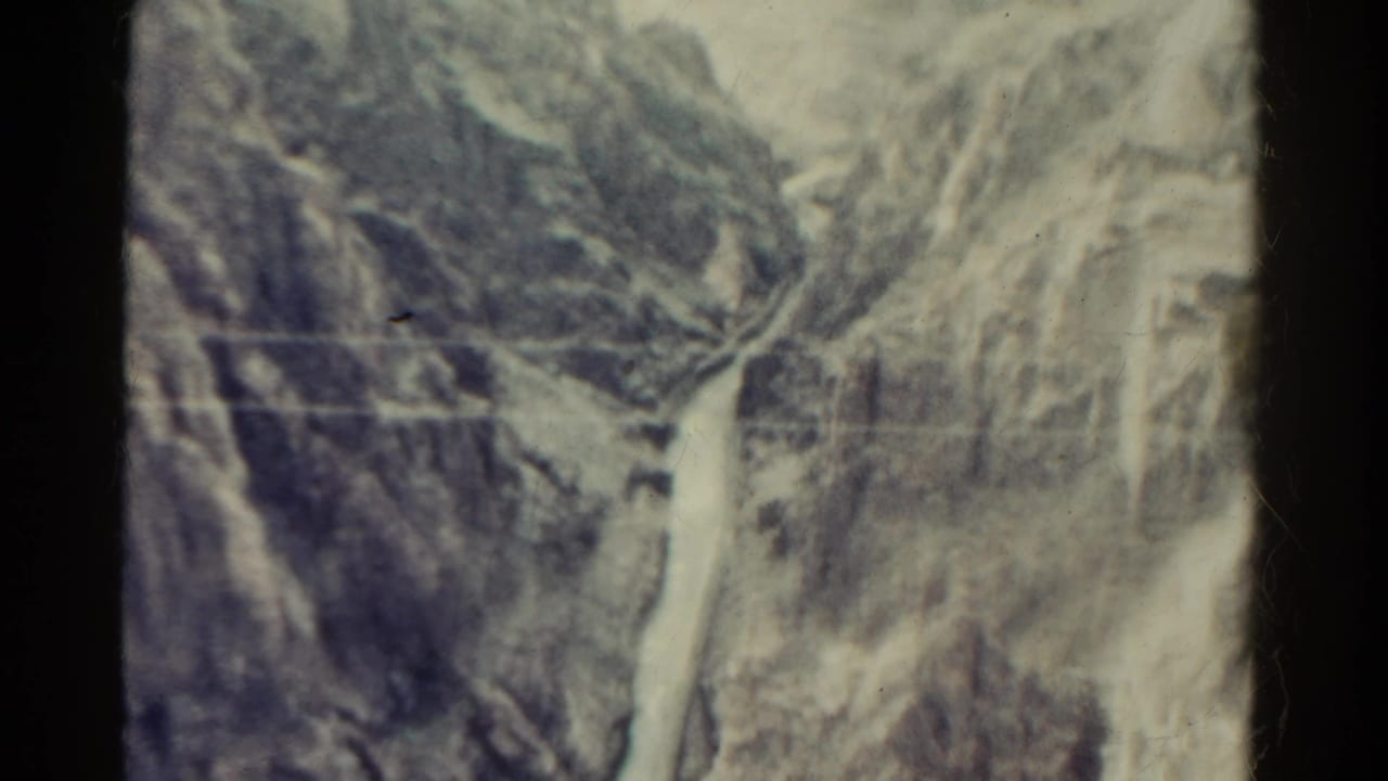 Rocky mountain terrain with pale exposed slopes and a narrow path or watercourse below.