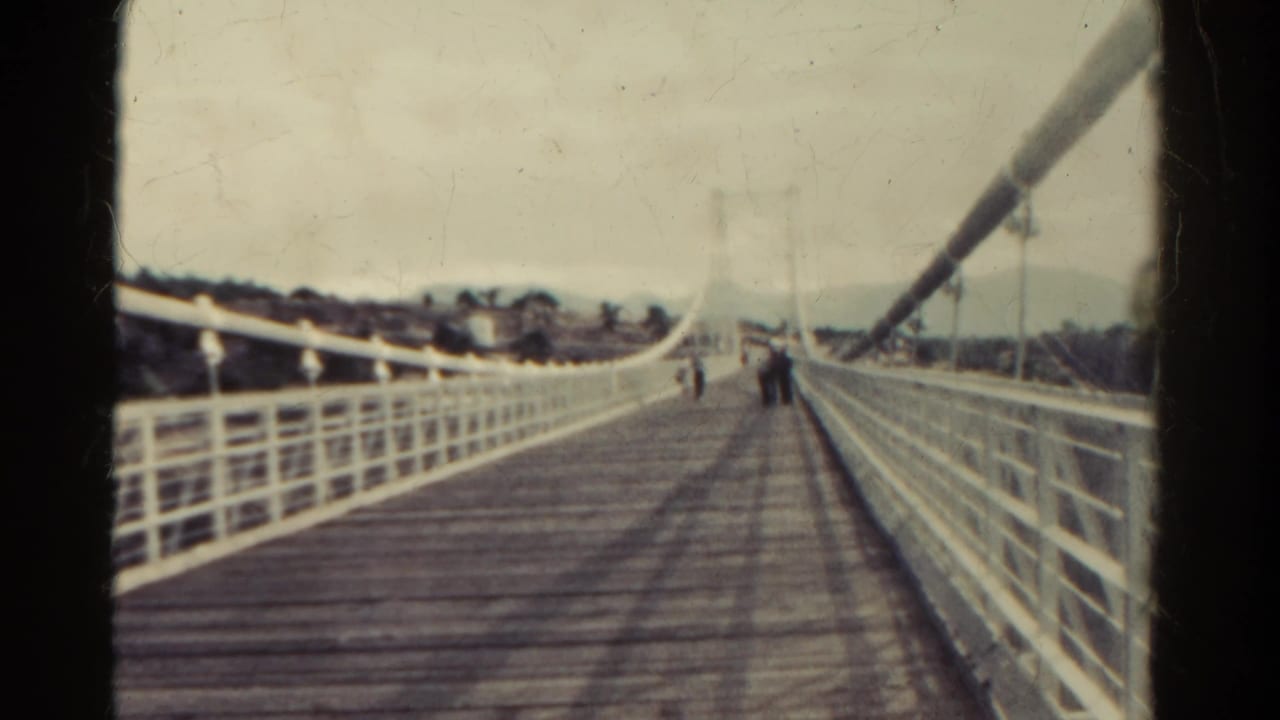 White suspension bridge with wooden planks and distant walkers.