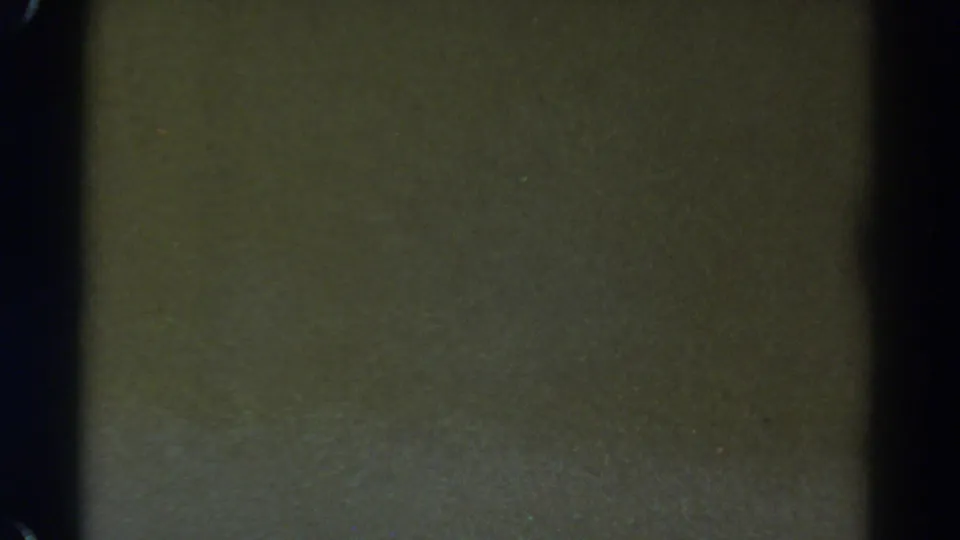 Underexposed 8mm frame from the Colorado clip, showing mostly dark film texture and frame-edge shadow.