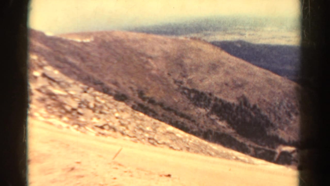 Pale rocky mountain slope descends toward a dark valley.