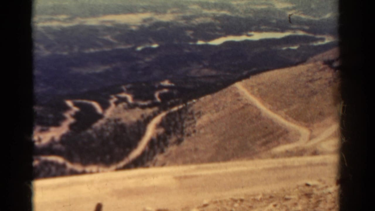 High view of pale dirt roads winding across sandy mountain slopes and darker brush below.