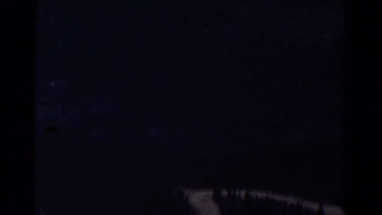 Dark, underexposed mountain view with blue haze and a pale diagonal landform near the lower right.