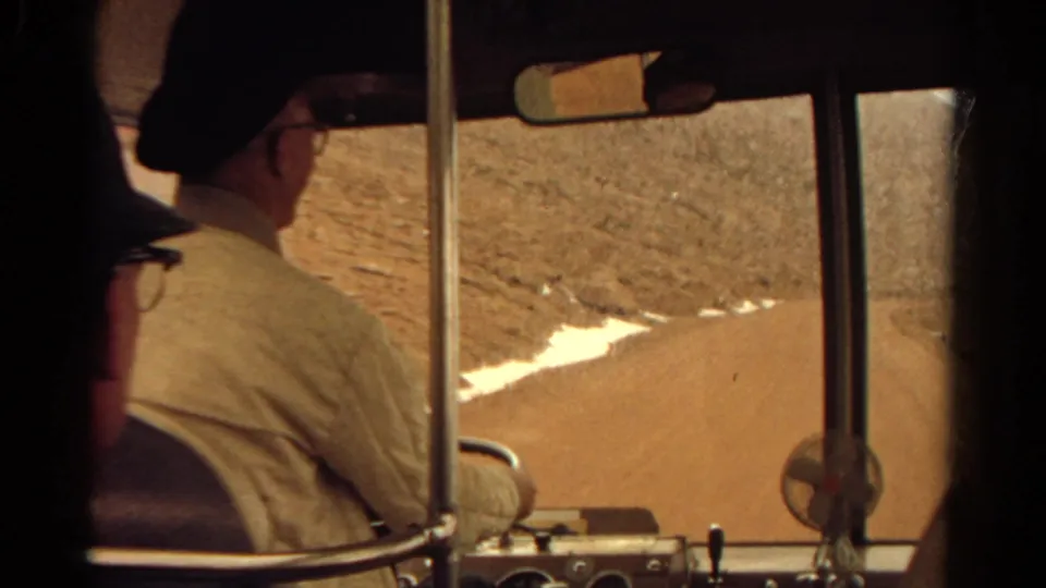 Final frame from the 1967 Colorado clip showing the driver from behind as the road curves through an arid landscape.