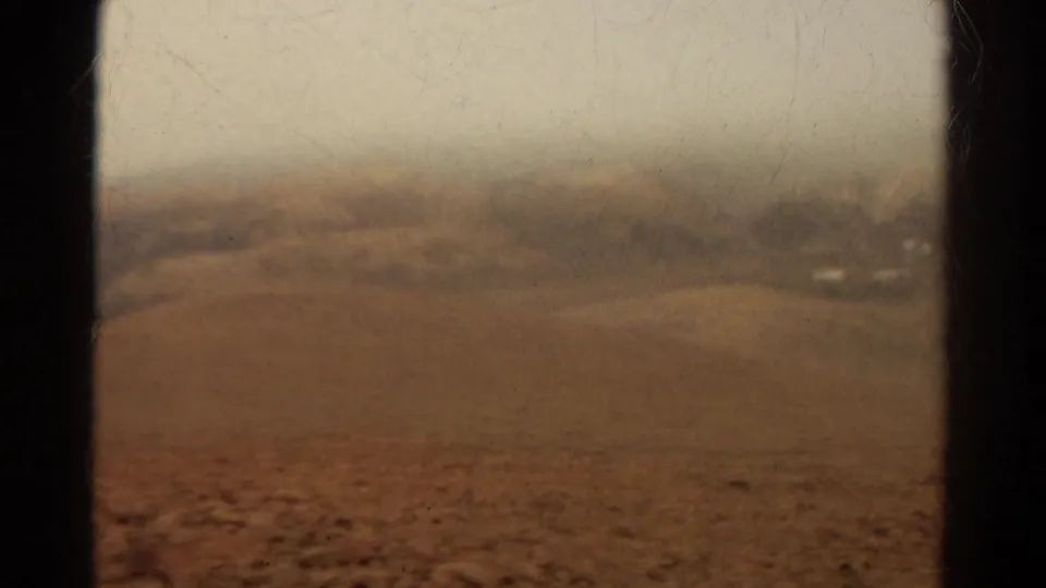 1967 Colorado home-movie view of hazy brown hills through a bus or vehicle window, with soft focus and dark frame edges.