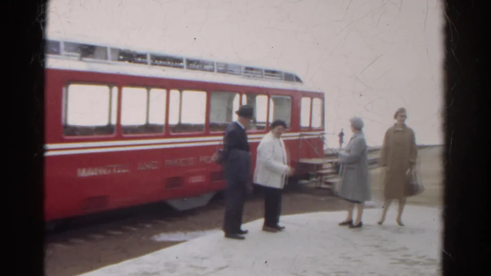 On the snowy Colorado platform, the group shifts positions beside the red Manitou and Pike's Peak railway car during the brief exchange.