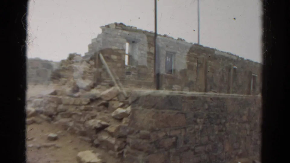 1967 Colorado 8mm frame showing crumbling stonework, rubble, a raised wall edge, and a weathered doorway opening.