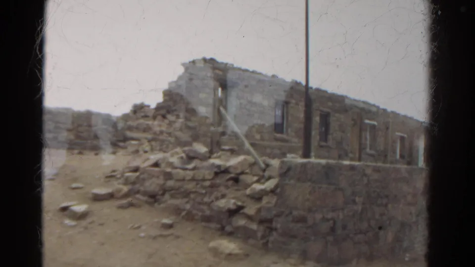1967 Colorado 8mm frame showing weathered stone ruins, rubble, and dry terrain under a pale sky.