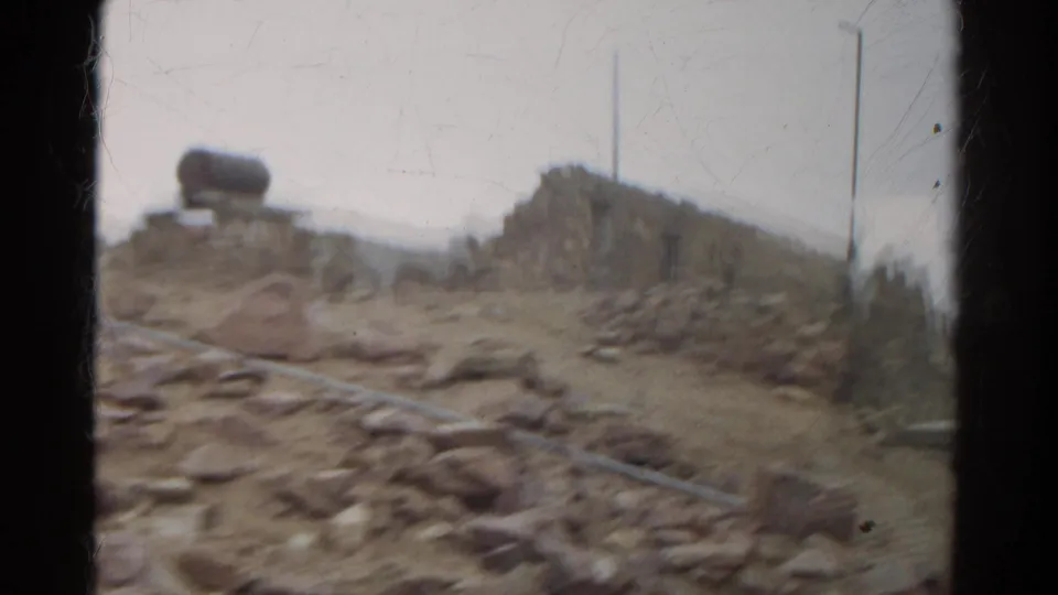 Motion-blurred 8mm view of dry Colorado terrain, scattered stones, and a low ruin during a 1967 sightseeing trip.