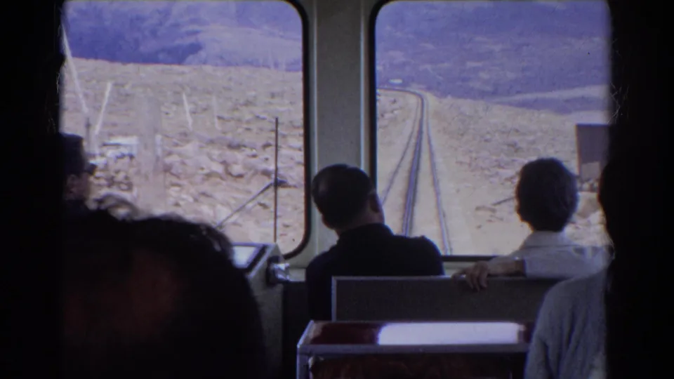 1967 Colorado home-movie view from inside a train, with passengers watching a curving rail line through rugged terrain.