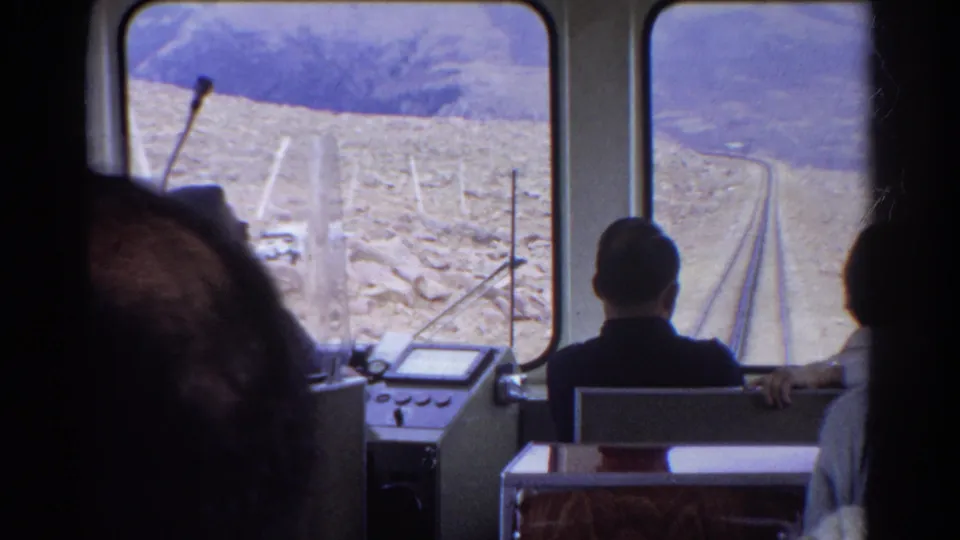 Home-movie view from inside a 1967 Colorado railway car, with passengers facing front windows and rails ahead.
