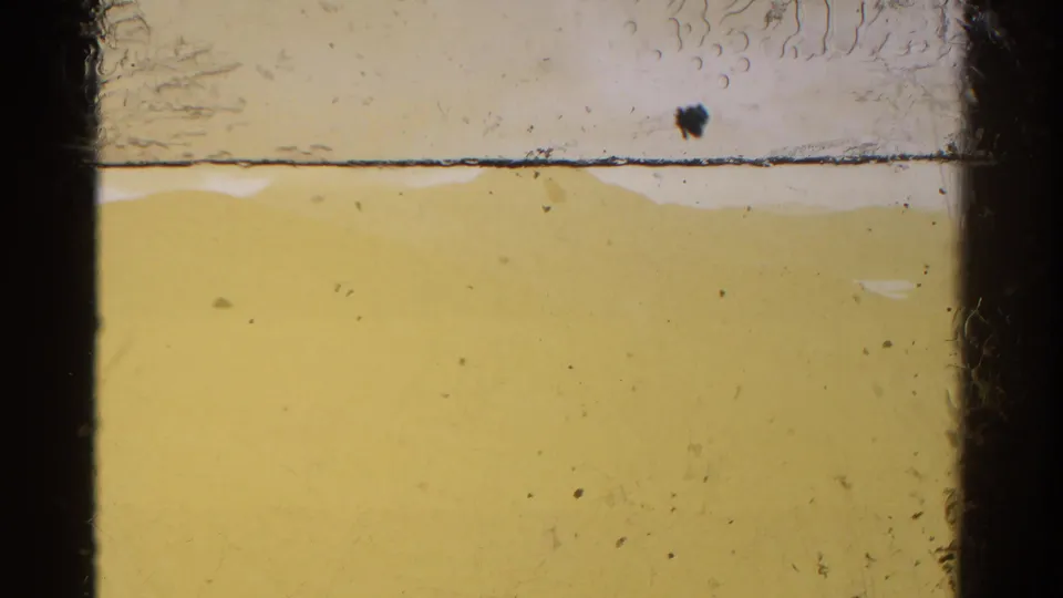 A soft, yellow-tinted 8mm frame from the Colorado 1967 clip, mostly obscured by exposure and film edge markings.