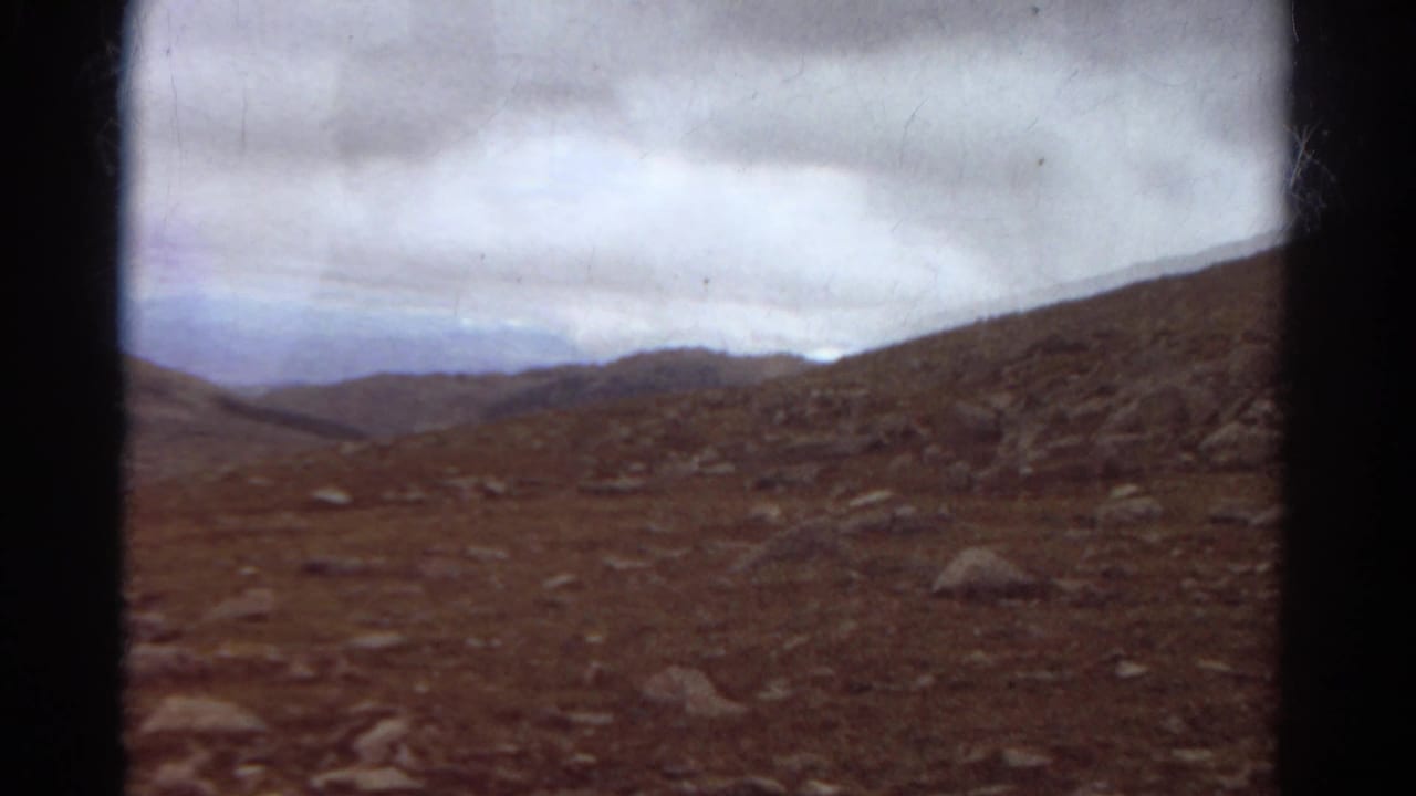 Rocky barren hillside beneath a heavy cloudy sky with dark 8mm frame edges.