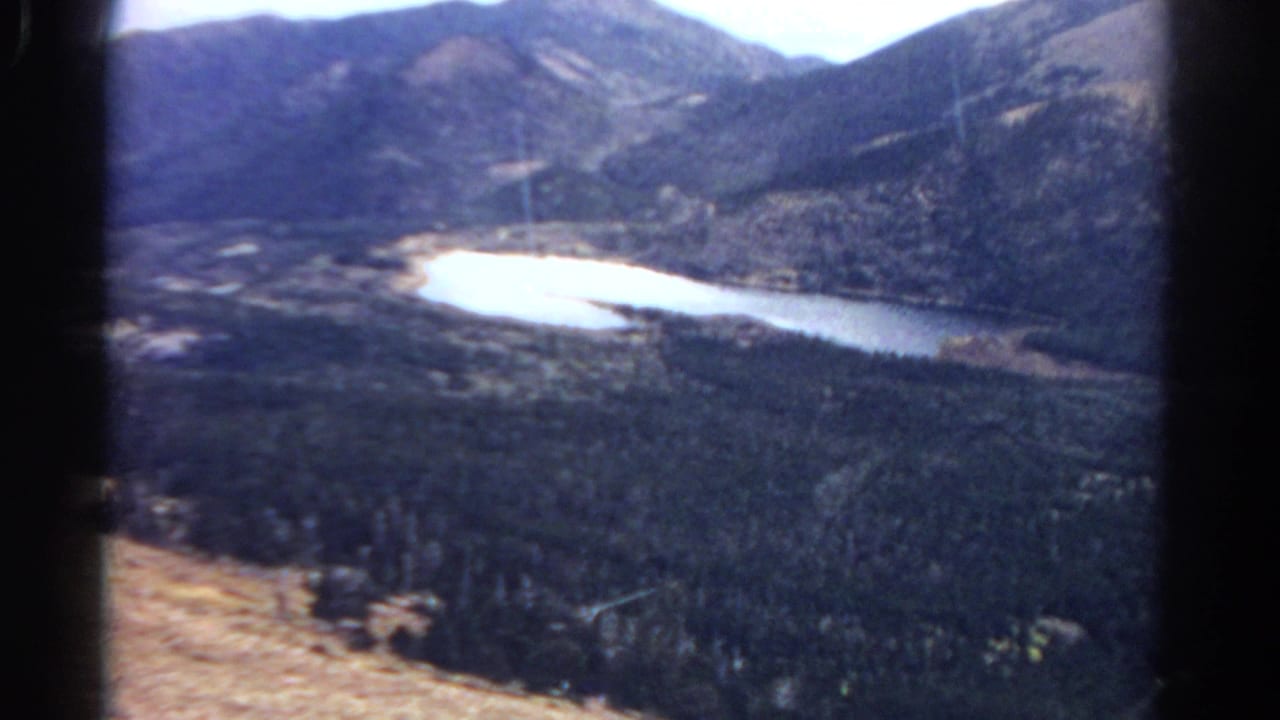 Wide mountain overlook with bright water curving through forested terrain.