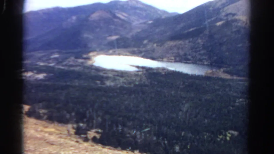 1967 Colorado landscape frame with soft focus, dark borders, forested slopes, and reflective valley water.
