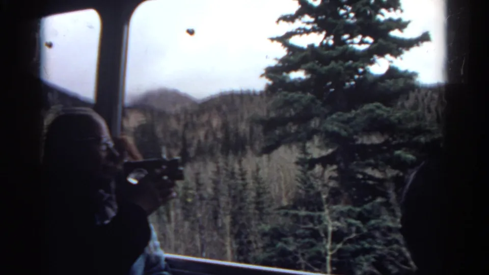 A person in a vehicle appears to take photographs of Colorado mountain scenery through the window during a 1967 home-movie drive.