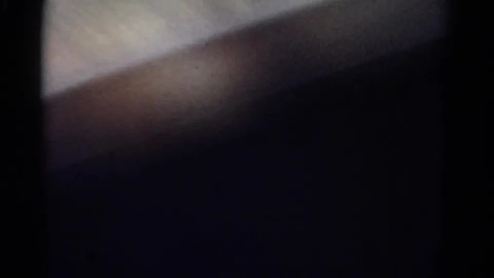 End frame from the 1967 8mm clip, largely obscured by a dark foreground shape with a small pale window-lit area visible.