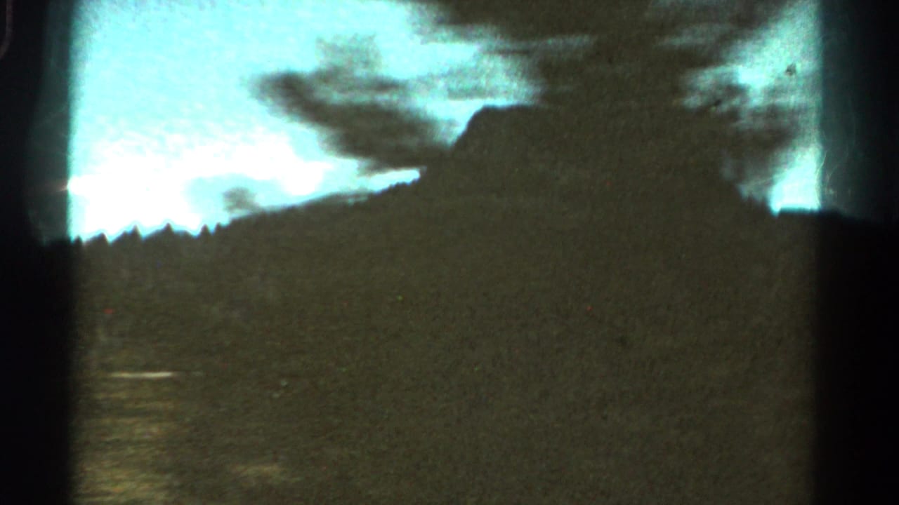 Dark mountain ridge and tree silhouettes against a bright blue sky.
