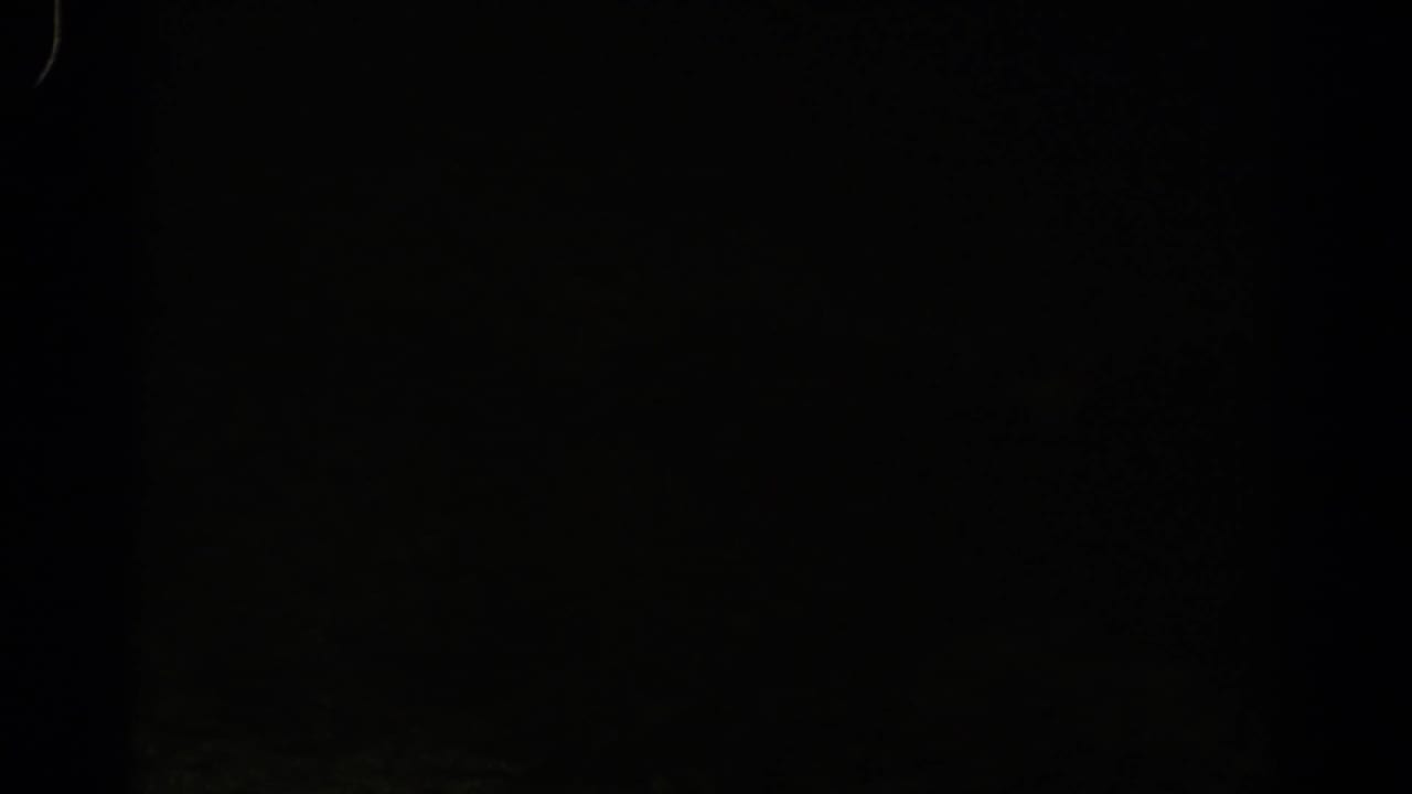 Dim 1967 Colorado 8mm frame with heavy darkness, film borders, and a faint green-toned snowy slope barely visible at the right.