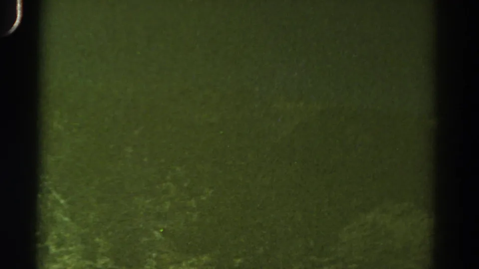 Damaged green-tinted 8mm frame from the 1967 Colorado clip, with little visible scenery beyond grain and frame edges.