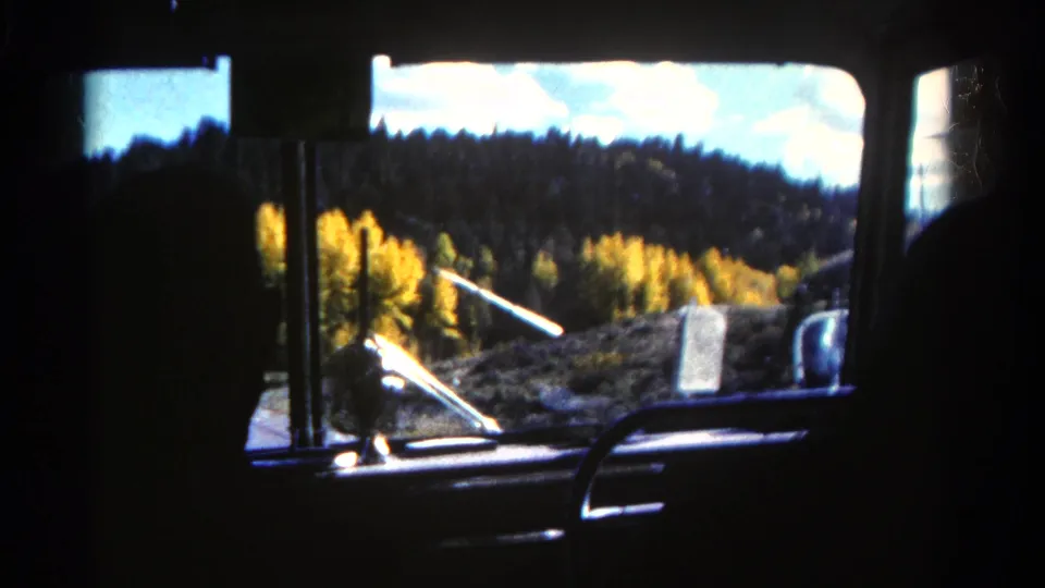 1967 Colorado 8mm frame from inside a vehicle, showing a passenger silhouette against forested hills and yellow foliage.