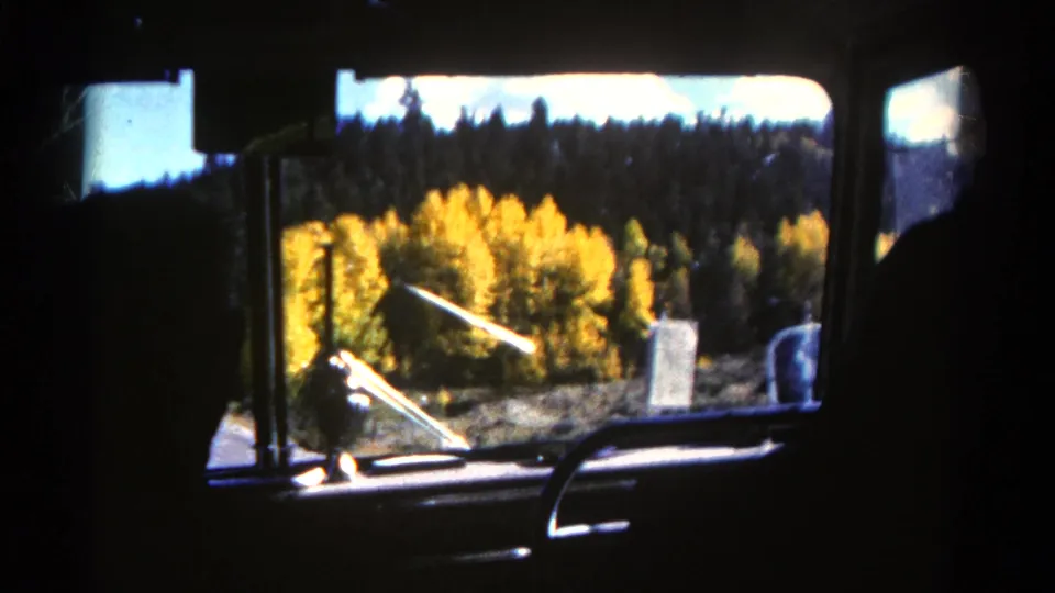 1967 Colorado home-movie frame showing a moving car interior and autumn trees outside the window.