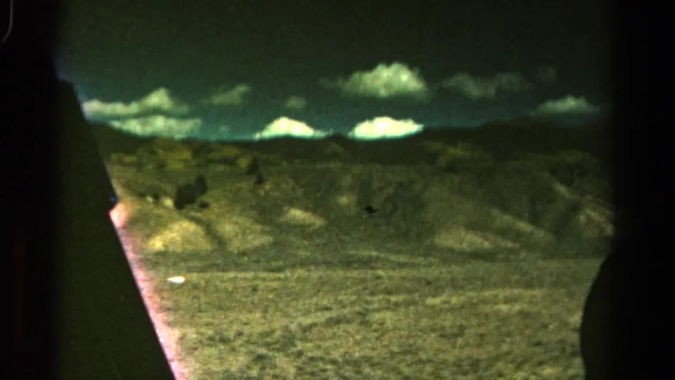 1967 Colorado road-trip view of arid open ground, low hills, and clouds, partially framed by the vehicle interior.