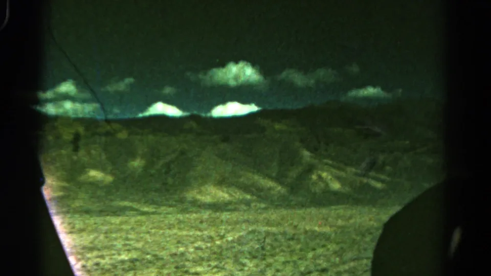 1967 Colorado home-movie frame showing rolling hills, bright clouds, and dark framing from the vehicle or film gate.