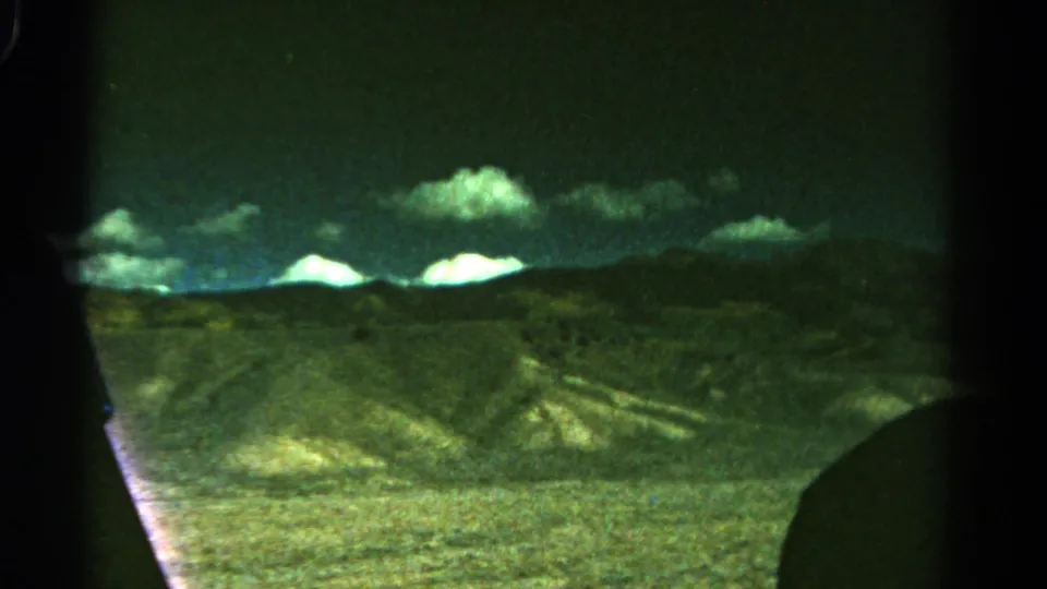 1967 Colorado 8mm frame showing open land, rolling hills, distant mountains, and bright clouds with visible home-movie grain.
