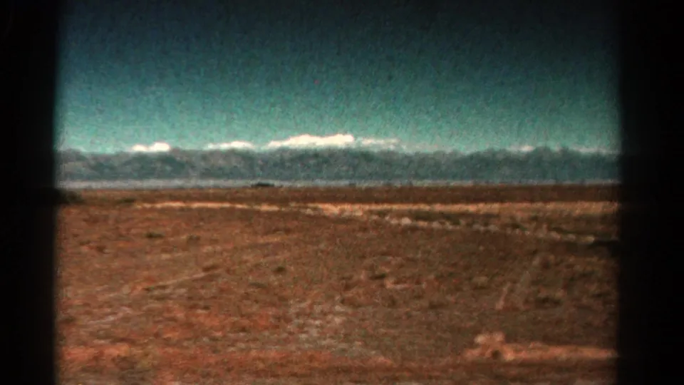 1967 Colorado 8mm frame showing a broad dry plain and distant mountain ridge beneath a lightly clouded sky.