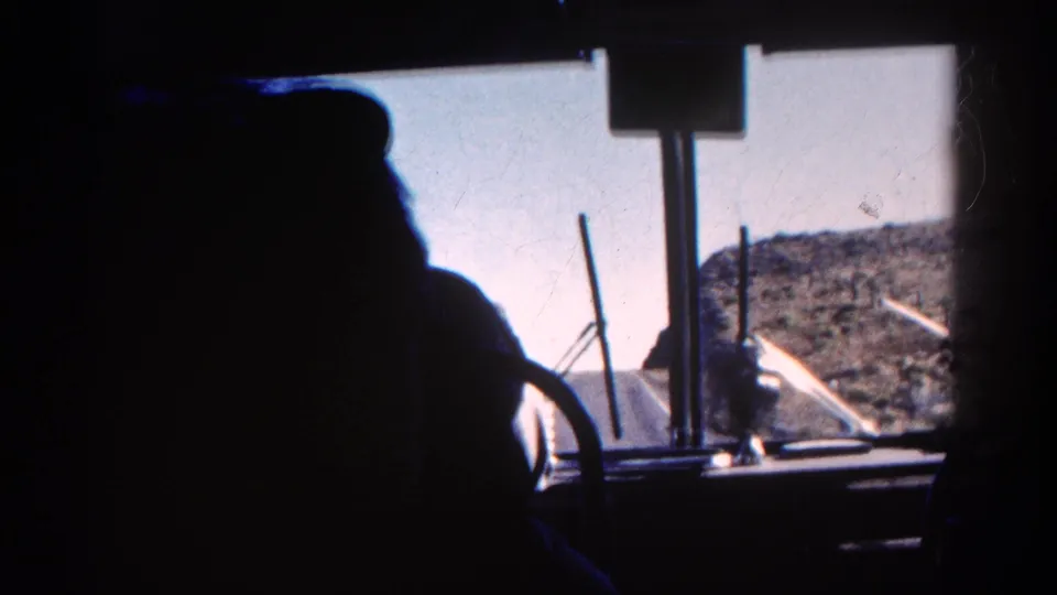1967 Colorado 8mm cab perspective with silhouetted operator or passenger, windshield fittings, pale sky, and rocky mountain slope visible ahead.