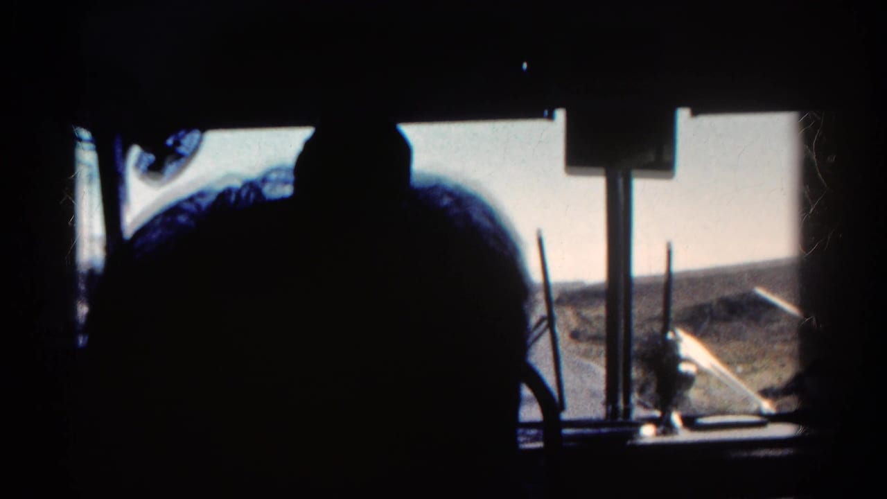 Interior bus view in Colorado, 1967, with a dark passenger profile against bright windows and dry rolling terrain outside.
