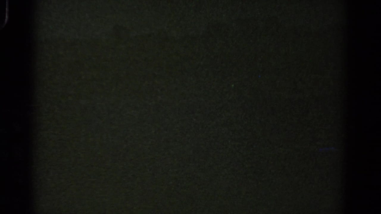 Underexposed 1967 8mm Colorado frame showing mostly darkness, greenish film texture, grain and gate-edge shadowing.