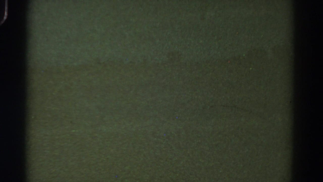 Dark green washed-out frame with grain, dust, and a black vertical band at left.