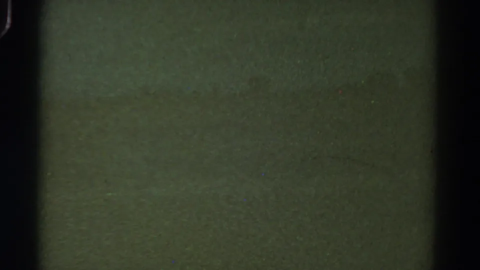 Obscured 1967 Colorado 8mm frame showing green tonal texture, heavy grain, dust, and a dark vertical film-edge band.
