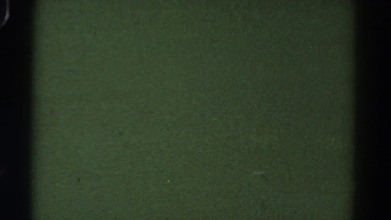 Green-tinted dark film frame with vertical gate shadows and visible grain.