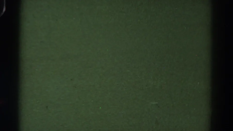 1967 Colorado 8mm frame showing green-black film texture, dark gate bands, dust specks, and no identifiable subject.