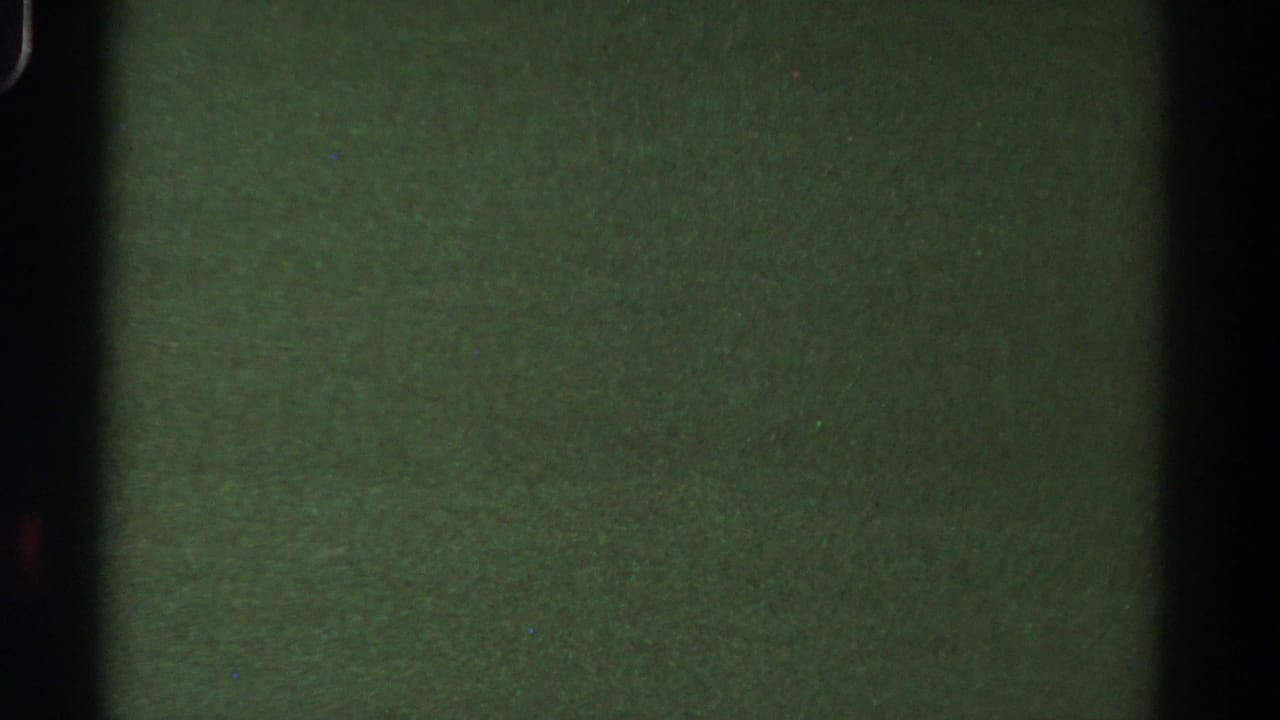 1967 Colorado 8mm frame with a central gate-like shadow, muted green exposure, grain, and small dust marks.