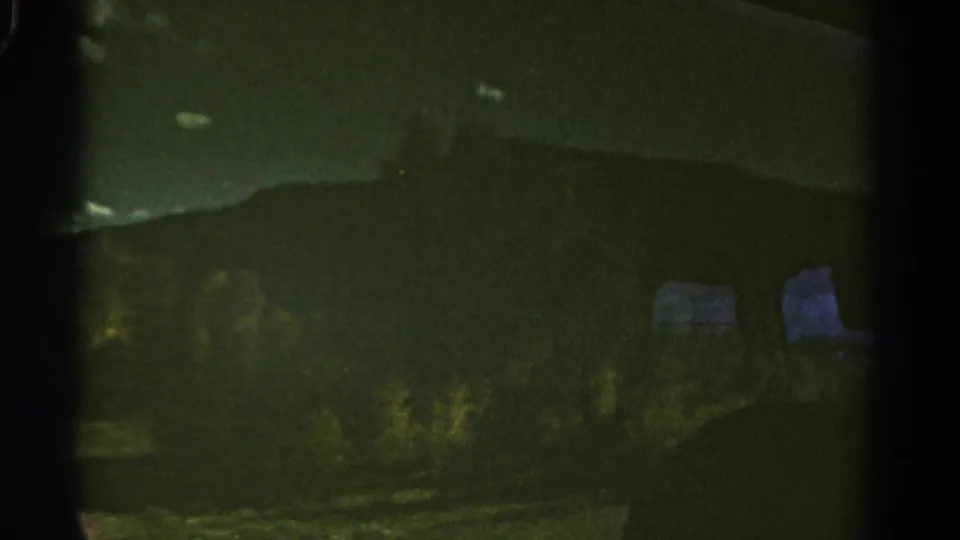 The final 1967 Colorado train-window frame shows a dim mountain outline through glass, with greenish exposure and passing foreground blur.