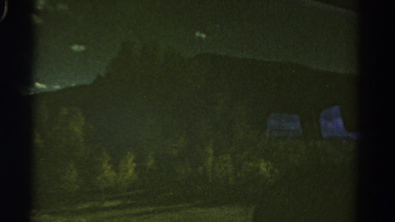 1967 Colorado 8mm frame showing a dim mountain ridge and roadside vegetation seen through dark vehicle-window framing.
