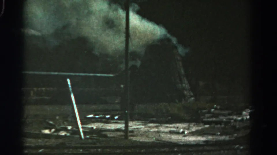 1967 Colorado 8mm frame showing smoke rising beside a dark rural structure and wet-looking ground.