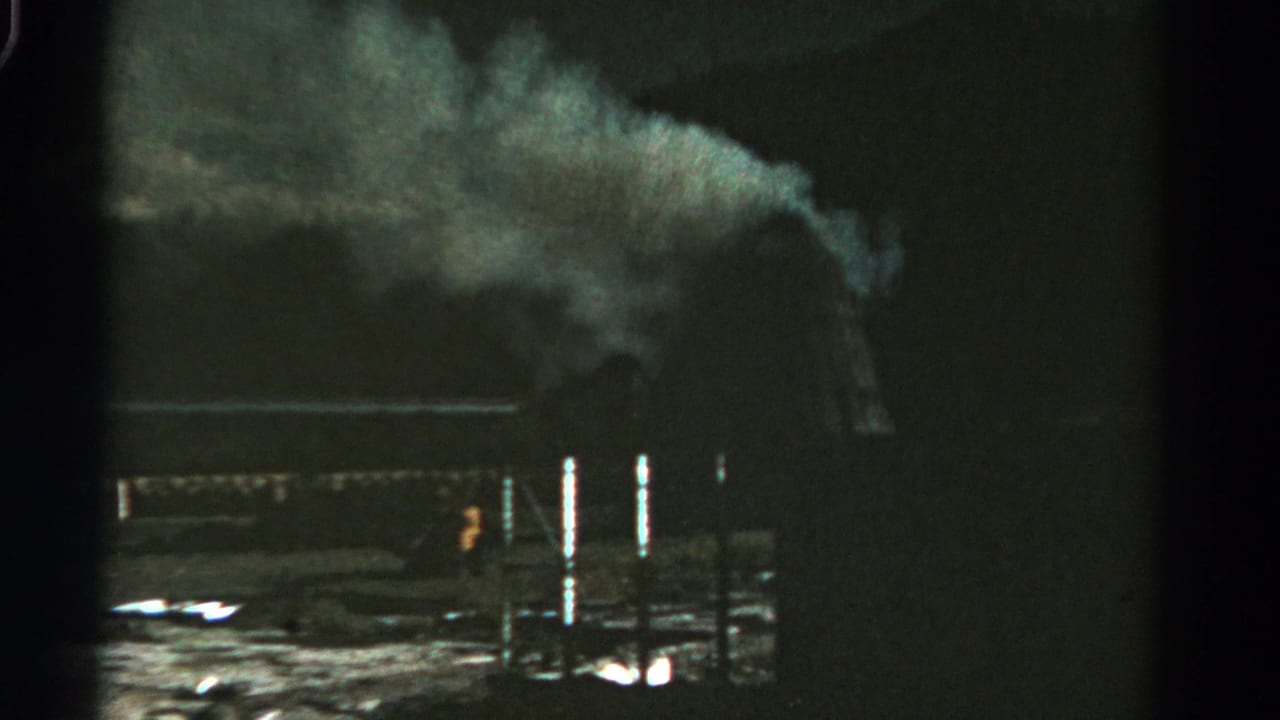 Large smoke plume above a dark factory area with posts and low reflective highlights.