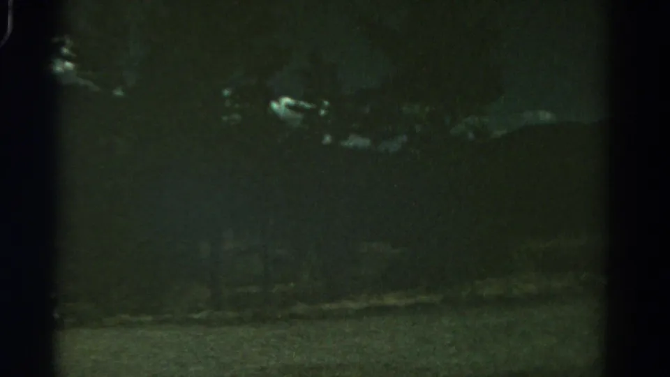 1967 Colorado home-movie frame showing dim clouds against a dark sky above a barely visible landscape.